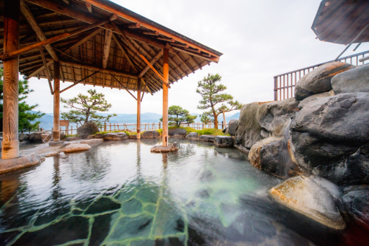 【1階湖上露天風呂‐千年の湯】庭園にいるような和のおちつきと、解放感ある景色。