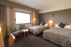 【デラックスツイン】贅沢な眠りをお届けする広々ベッドと、上層階から望む横浜の街並み