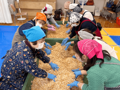 大きな樽でほかほかの蒸し大豆と麹、塩を混ぜ合わせます