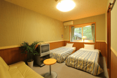 【客室一例】洋室（シャワー付）。ツインベッドルーム。ソファーベッド１台入れて３名までご宿泊可能。
