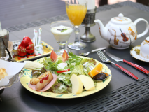 朝食は焼き立てパンと野菜プレート。夏季は緑に囲まれたテラス席でお召し上がりいただけます。