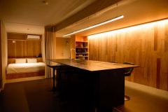 最大1棟6名のGlambase客室は、天然木の壁と暖色LEDが包むリビング一体型レイアウト。3m超のアイランドで料理やリモートワークも快適。電子レンジ、IH、冷蔵庫、食器で雨の日も心配なし。奥のダブルベッドは高反発マットレスを採用し深い眠りを約束。遮光カーテンで空間を仕切ればプライベート感も確保。センシングサウナで汗を流した後、冷えたドリンクを片手に仲間と語らう贅沢な夜を。