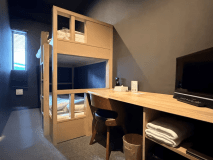 各客室は、黒を基調としたシックな空間に、BUNK BED（二段ベッド）とデスクを配した設え。滑らかな肌触りの木材を使用したオーダーメイドの家具は、しっかりした造り。高反発マットレスで、快適な睡眠を提供しています。※テレビのある客室と、テレビのない客室があります。