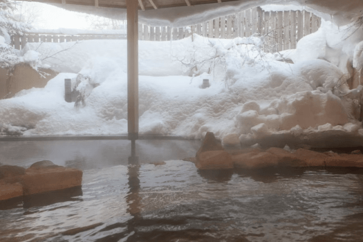 【大浴場／露天風呂】白一色に染まる冬の露天風呂。四季折々の景観をお愉しみくださいませ。