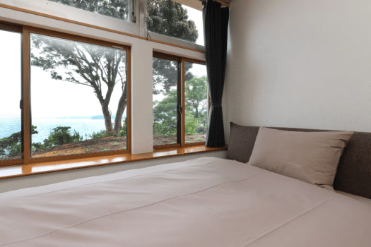 【海の見えるツインルーム】ベッドルームの大きな窓からは、日本の渚百選に選ばれた青海島の雄大な景色が一望できます。