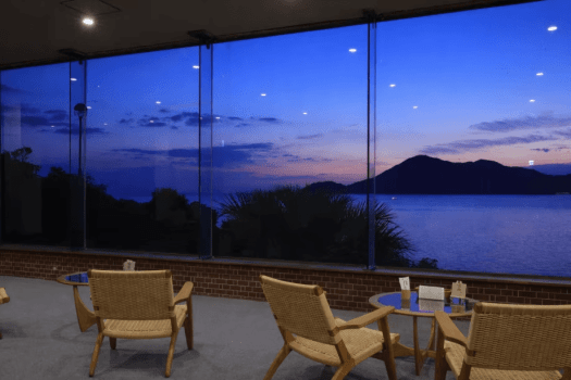 【海の見える展望ラウンジ】夕暮れの光が差し込むラウンジでは、海景が一日の終わりを静かに告げます。心を休めるための、上質なひとときがここにあります。