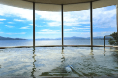 【悠久の湯／オーシャンビュー展望大浴場】美肌の湯として知られる、静かな秘湯。晴れた日には輝く海景を、曇りや雨の日にも静謐な癒しを――いつ訪れても、ここでしか味わえない安らぎのひとときを。