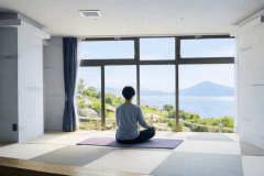 【ヨガ】大きな窓の向こうに広がる青い海と緑の稜線。海外のリトリートを思わせる開放感の中、畳の温もりに包まれながら心身がゆっくりほどけていく。