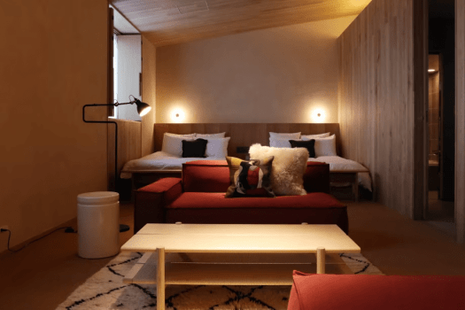 【111／Design for Living】
レッドのモジュラーソファと白いローテーブルが手前に広がり、奥のベッドへと視線が続きます。構造と用途に根ざしたデザインが、この部屋での夜をゆったりと、深く整えてくれます。