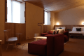 [111/Design for Living] An Ercol loveseat sits casually by the window, and a red modular sofa leads to the bed. Soft light streams in from the north-facing window, making this room a comfortable space to simply be in, both morning and night.