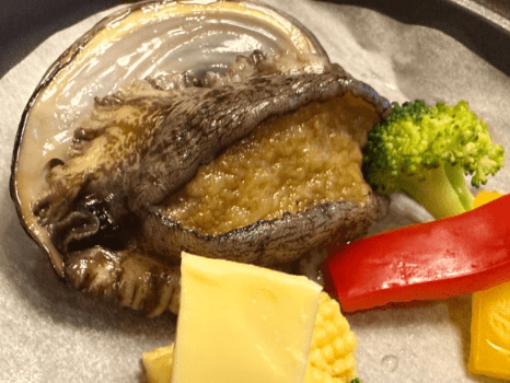 Grilled abalone, carefully cooked to bring out its rich flavor and delicate texture &mdash; a true taste of Hokkaido seafood.