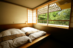 303号室：お布団のそばには大きな窓があり、いつでも自然を感じられます。
