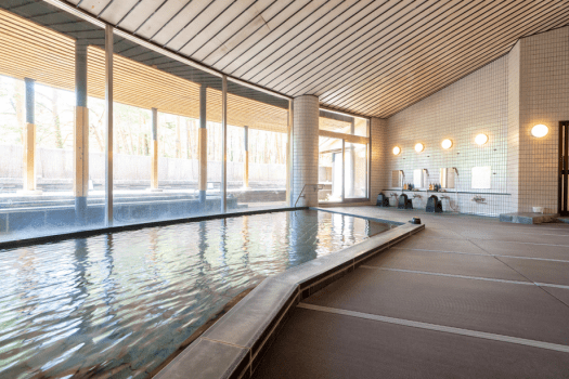 【八ヶ岳ホテル風か】大浴場　内湯（麗水備長炭風呂）｜大浴場の床は畳敷きです。濡れても滑りにくく、肌触りも柔らか。断熱性があるので床からの冷え込みも和らげます。