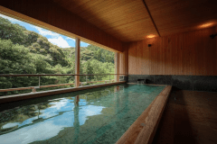2階こもれびの湯：視界の先に広がる木々の緑と青空。川からの風を感じながら、時間を忘れて湯に浸かると、今まで思い出さなかったようなアイデアも浮かんできそうです。