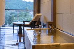 【露天風呂付・渓流側】長門 スイート：のどかな風景を眺められる源泉かけ流し露天風呂。檜の香りとともに、柔らかな湯ざわりをお愉しみくださいませ。