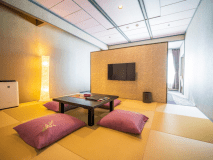 新・和洋室は琉球畳が敷かれたモダンな空間。秋保の里山を一望する窓際にベッドが配置され、朝の目覚めが楽しみなる客室（新・和洋室）