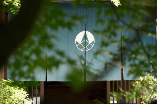 【お客様をお迎えする正面玄関】特徴的な暖簾は、火・炎・ファイヤープレイスをモチーフにした紋です。